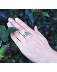 Men's 18K yellow gold ring with a rectangular 2.90 ct. Colombian emerald and diamond accents on a hand.