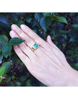Men's 18K yellow gold ring with a rectangular 2.90 ct. Colombian emerald and diamond accents on a hand.