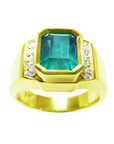 Clearly visible the emerald-cut natural colombian emerald bezel set in this yellow gold men's ring topside profile.