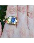 Men's 18K yellow gold solitaire ring with a vivid blue octagonal sapphire, bezel set.
