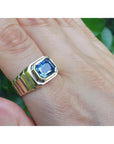 Men's 18k yellow gold ring with a vibrant blue octagonal emerald cut sapphire, bezel set east-west.