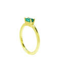 A yellow gold minimalist solitaire emerald ring in its side position.