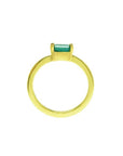 A yellow gold minimalist solitaire emerald ring showing the lateral profile new.