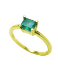 Tilted position for this minimalist emerald solitaire ring representing May's birthstone jewelry, topside and band ring profile visibles.