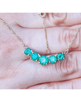 14K gold necklace with five round, medium green Colombian emeralds in elegant basket settings.