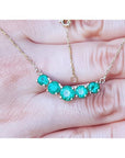 14K gold necklace with five round, medium green Colombian emeralds in elegant basket settings.