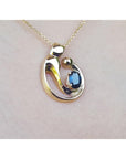Yellow gold mother and child pendant with blue natural sapphire pending from a woman's neck