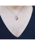 14K yellow gold mother and child sapphire slider pendant necklace on a woman's neck.