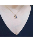 14K yellow gold mother and child sapphire slider pendant necklace on a woman's neck.