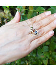 14K yellow gold mother and child sapphire slider pendant necklace held in a hand.