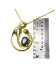 14K yellow gold mother and child pendant with an oval blue sapphire, shown with a ruler.