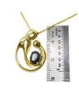 14K yellow gold mother and child pendant with an oval blue sapphire, shown with a ruler.