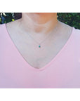 0.27 ct Colombian emerald pendant in 14K white gold, worn on a woman's neck over a pink top.