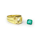 A gold ring mounting with a square-cut emerald on a side to be set