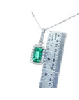 1.70 ct Muzo Colombian emerald pendant with diamond halo in 18K white gold, shown with ruler for scale.
