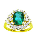 A 14K yellow gold ring featuring a Muzo Colombian emerald surrounded by a halo of diamonds, showcased from a topside perspective.