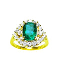 A 14K yellow gold ring featuring a Muzo Colombian emerald surrounded by a halo of diamonds, showcased from a topside perspective.