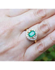 1.43 ct cushion-cut Muzo Colombian emerald ring with marquise diamond halo in 14K yellow gold.