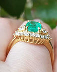 A Muzo born colombian emerald ring in yellow gold on a person's hand.