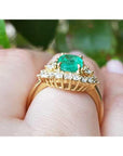 1.43 ct cushion-cut Muzo Colombian emerald ring with marquise diamond halo in 14K yellow gold.