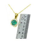 Round 0.61 ct deep green Colombian emerald halo diamond necklace in 14k yellow gold, next to a ruler.