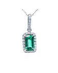 Natural Muzo emerald pendant with diamond accents on a topside view.