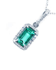 Emerald green gemstone pendant with diamond accents on a white background