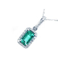 Emerald green gemstone pendant with diamond accents on a white background
