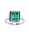 This Muzo colombian emerald solitaire ring displays its topside view of the rectangular emrald-cut prong set in 18k white gold.