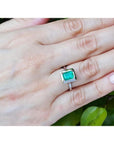1.50 carat Muzo Colombian emerald solitaire ring in 18K white gold on a hand.