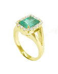 Half side profile displaying a yellow gold emerald ring with split shank.