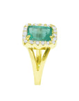 A side view of a natural emerald and diamond ring yellow gold/