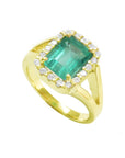 The tilted position of this halo diamond emerald ring shows the top and side profile.