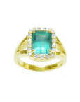 This emerald-cut Muzo Colombian emerald ring for women has a halo of natural diamonds and is crafted in 14k yellow gold.