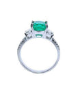 18K white gold ring with a cushion cut emerald and trapezoid side diamonds.