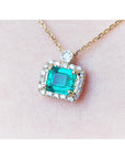 1.31 ct emerald-cut Muzo Colombian emerald necklace with diamond halo on 14K yellow gold chain.