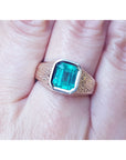 Gold men's ring with a Muzo colombian emerald bezel set on a finger.