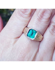 Gold ring for men with a bezel set natural colombian emerald on a finger.