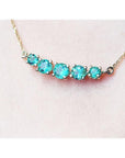 14K gold necklace with five round, medium light green Colombian emeralds, graduated in size.