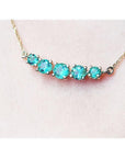 14K gold necklace with five round, medium light green Colombian emeralds, graduated in size.