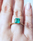 Emerald-cut Muzo Colombian emerald ring with a medium deep bluish-green stone on a gold band.