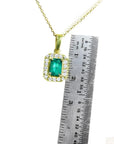 0.75 ct. GIA certified F1 Colombian emerald pendant in 18k yellow gold with diamond halo, next to a ruler.