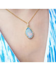 Australian opal pendant with fiery red-orange play-of-color, halo diamonds, and 18K yellow gold chain.