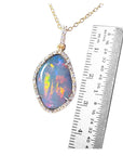 Opal pendant necklace with a ruler for scale on a white background.
