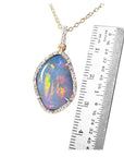 Opal pendant necklace with a ruler for scale on a white background.