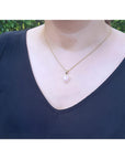 Heart-shaped Australian white opal pendant with red fire, diamond halo, on a yellow gold chain.