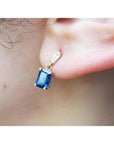 14K yellow gold dangling earrings with emerald cut blue sapphires and tapered baguette diamonds.