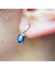 14K yellow gold dangling earrings with emerald cut blue sapphires and tapered baguette diamonds.