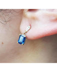14K yellow gold dangling earrings with emerald cut blue sapphires and tapered baguette diamonds.