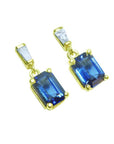 14K yellow gold earrings with emerald cut blue sapphires dangling from baguette diamonds.